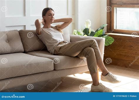 Calm Millennial Woman Relaxing On Couch With Eyes Closed Stock Photo