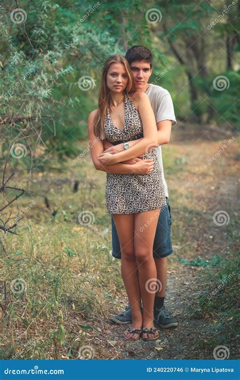 Young Man Hugs His Beloved Standing Behind Her A Happy Couple In Love Spends Time Together In