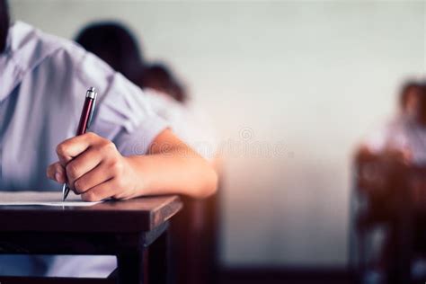School Student Is Taking Exam And Writing Answer In Classroom For