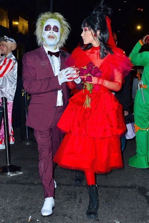 Two People Dressed Up As Clowns Walk Down The Street At An Event In Costume