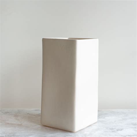 A White Square Vase Sitting On Top Of A Table