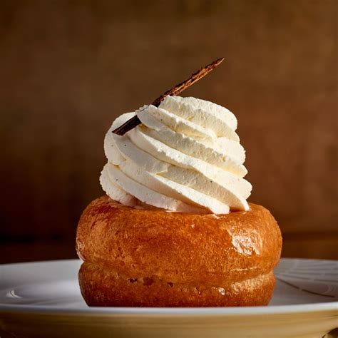 A Pastry With Whipped Cream On Top Is Sitting On A White Plate And Has