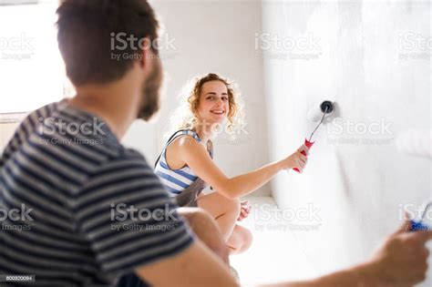 Young Couple Painting Walls In Their New House Stock Photo Download