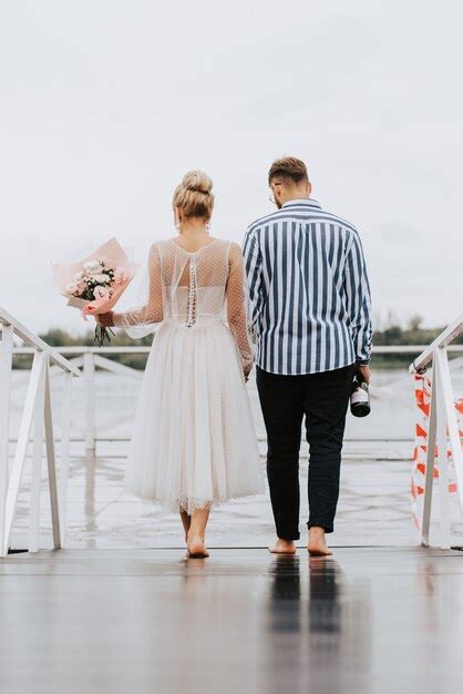 Premium Photo The Just Married On The Wharf The Bride And Groom Walk Barefoot Along The Pier