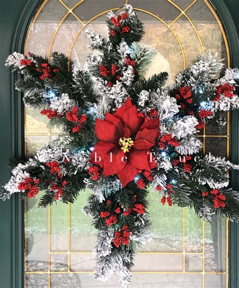 A Christmas Wreath With Poinsettis Pine Cones And Snow Flakes Hanging