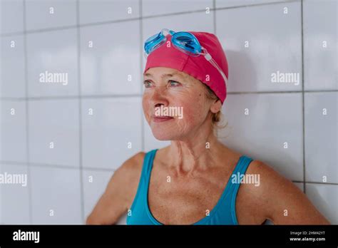 Active Senior Swimmer Woman Standing Against White Tiles Wall Indoors