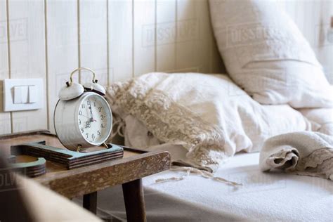 Unmade Bed Alarm Clock On Bedside Table Stock Photo Dissolve