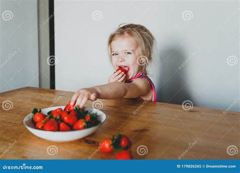 Cute European Girl Eating Strawberries A Beautiful Cheerful Blonde With Blue Eyes Stock Image