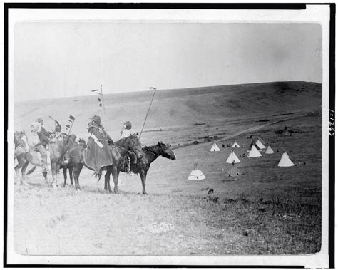 Four Atsina Indians On Horseback Overlooking Tepees In Valley Beyond