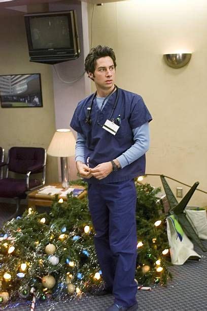 A Man In Scrubs Standing Next To A Christmas Tree
