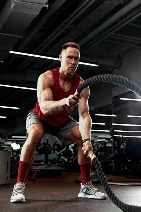 Sport Strong Man Exercising With Battle Ropes At The Gym With Athlete