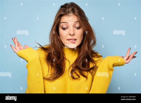 A Beautiful Brunette In A Yellow Sweater Stands On A Blue Background