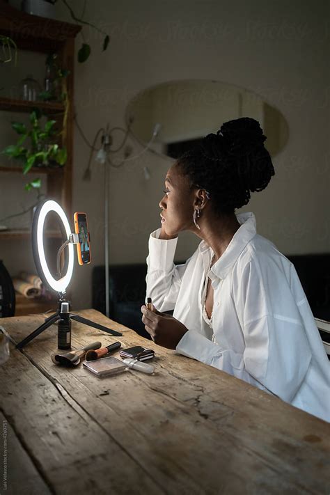 Black Woman Making Up Using Mascara In Front Of A Ring Light By