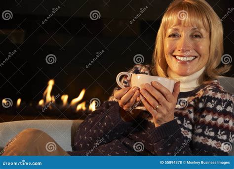 mogen kvinna som framme kopplar av av brand hemma arkivfoto bild av natt anläggning 55894378