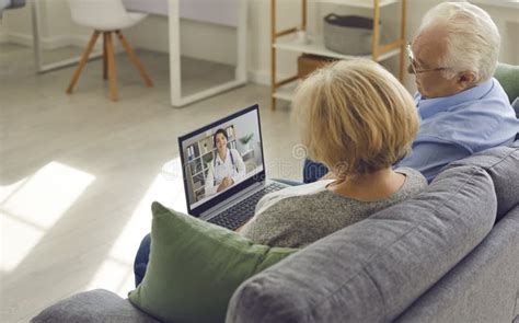 Senior Couple Sitting On Couch With Laptop And Having Video Call With