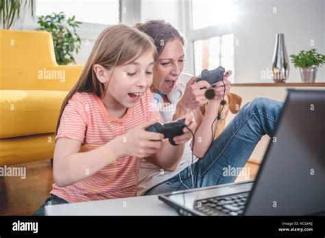 Mother And Daughter Playing Video Games On Laptop At Home Stock Photo