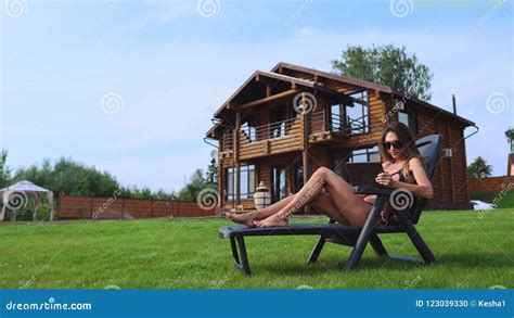 A Beautiful Woman Lying On A Sun Lounger In The Backyard Of Her Mansion