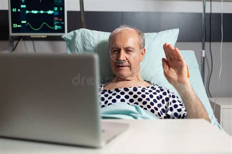 Cheerful Sick Senior Man Waving At Camera During Video Conference Stock