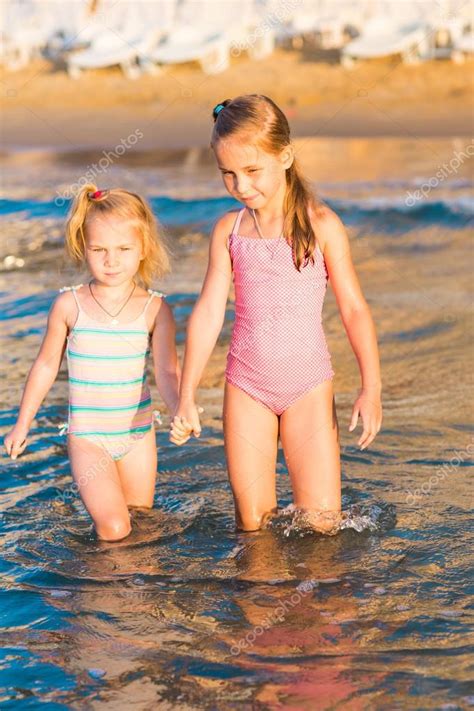 Две очаровательные дети играют в море на пляже Стоковое фото Len ik
