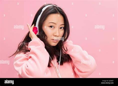 Smiling Cutie Cute Asian Young Lady In Pink Hoodie Sweatshirt With Cute Headphones Looks At You