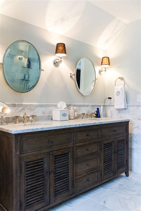 A white modern, marble topped double vanity bathroom with contemporary wall sconces, metallic and wood highlights and a white marble inlaid floor. Remodelaholic | Spacious Bathroom Inspiration