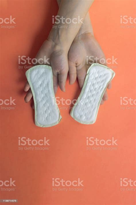 a white sanitary pad in womans hands on a pantone background with copy space absorbent item for