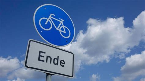 A Blue Sign That Says Ende With A Bicycle On It In Front Of Some Clouds