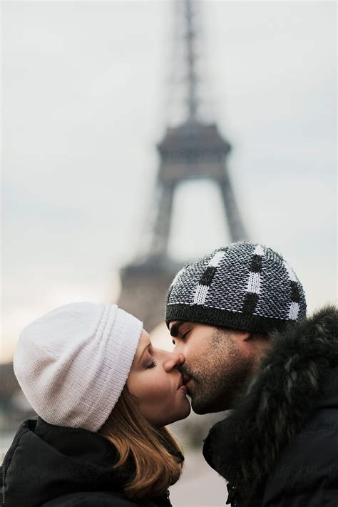 happy couple kissing and hugging in front of the eiffel tower in paris by stocksy contributor