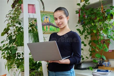 Portrait Of Teenage Smiling Girl Using Laptop Home Room Interior Stock