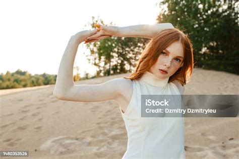 Portrait Of Flexible Redhead Woman With Raised Hands In Nature Stock