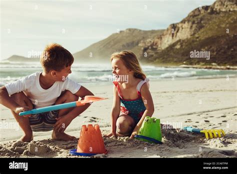 Two Children Playing With Sand On The Beach Small Boy And Girl