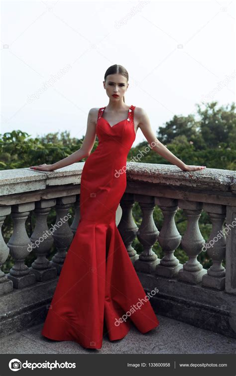 Великолепная молодая женщина с темными волосами в элегантном красном платье стоковое фото