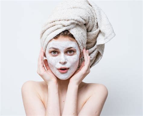 pretty woman with a towel on her head and a white mask against black dots on her face stock