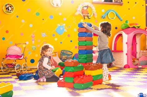 Premium Photo Two Girls Play With Big Bricks In Playroom