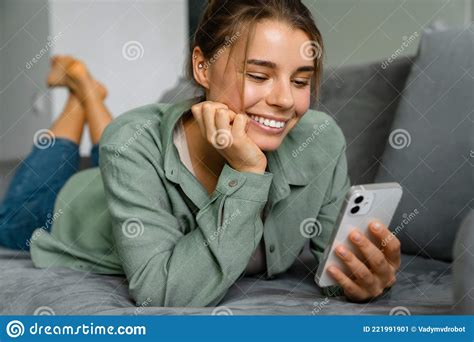 Happy Nice Woman Using Mobile Phone While Lying On Sofa Stock Image