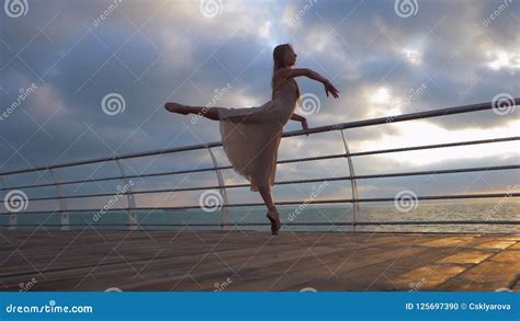 Dancing Ballerina In Beige Silk Dress And Pointe On Embankment Above