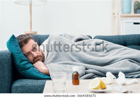 Man Wrapped In Plaid Lying On The Sofa Feeling Sick Illness At Home