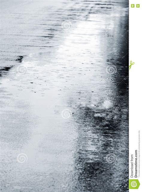 Grey Asphalt With Rain Puddles And Rain Drops Falling On It Stock Photo