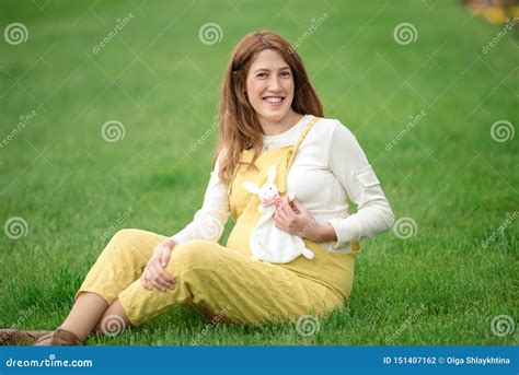 Expecting Young Female Mother Posing In Park Holding Plush Toy Stock