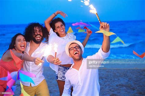 Young People Having Fun With Fireworks And Decoration On Beach High Res