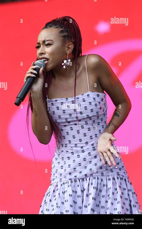 Singer Ravyn Lenae Is Shown Performing On Stage During A Live Concert