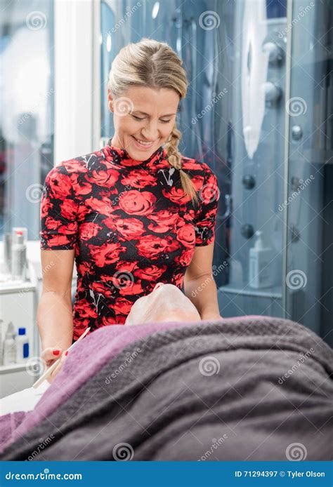 Beautician Smiling While Applying Face Mask To Client Stock Image