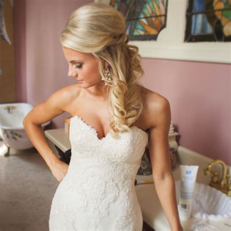 A Beautiful Blonde Woman In A Wedding Dress Standing Next To A Sink And Looking At The Mirror