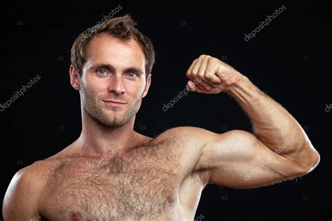 Closeup Portrait Of Muscular Man Flexing His Bicep Against Black