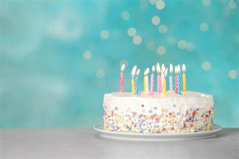 Birthday Cake With Burning Candles On Table Against Light Blue