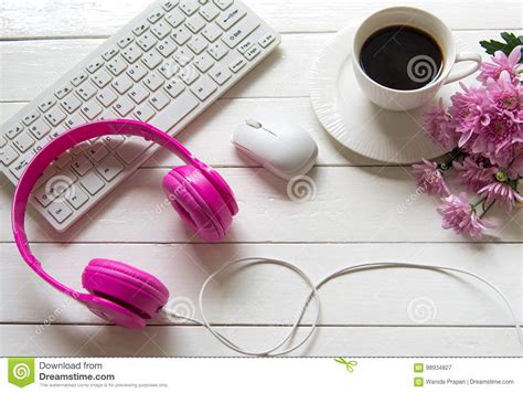Pink Headphones And Coffee Cup On Wooden Desk Table With Pink Flower