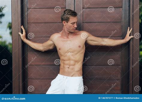 Retrato Del Hombre Deportivo Atractivo En Los Pantalones Blancos Con El Torso Desnudo Que