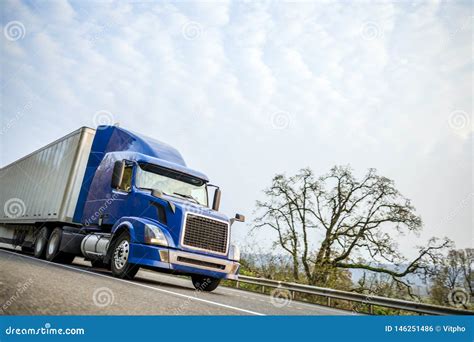Big Rig Blue Modern Semi Truck With Dry Van Semi Trailer Driving On The
