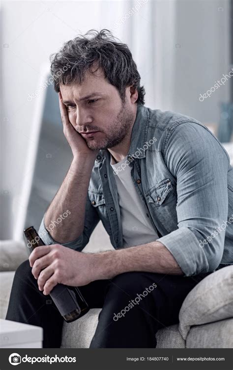 Sad Man Sitting With His Head Resting On His Hand And Thinking Stock