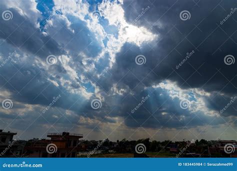 Heavenly Sun Rays Through Dark Clouds Against The Blue Sky Stock Photo